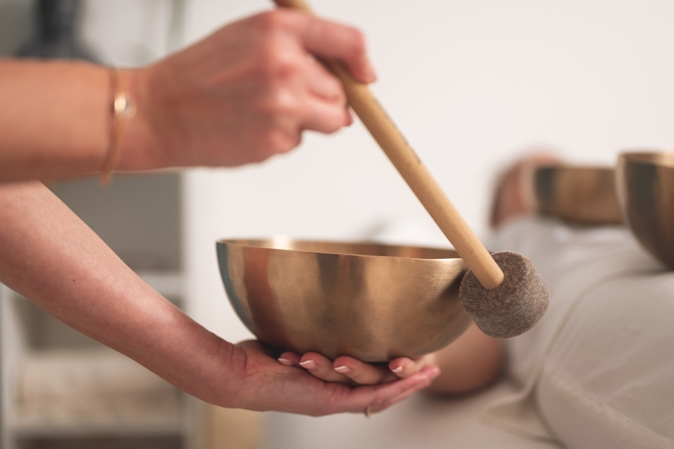 coach guiding womans hand to singing bowl while lying down